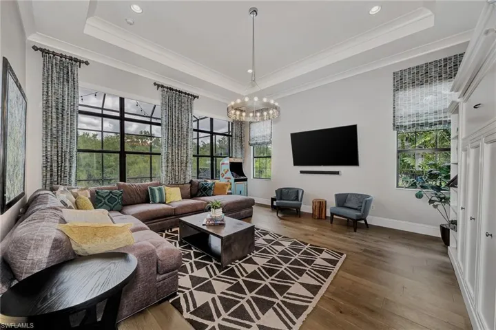 Living room with ornamental molding, a raised ceiling, and dark hardwood / wood-style floors