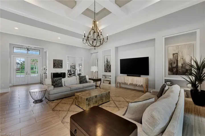 Living room featuring beamed ceiling, a notable chandelier, french doors, and coffered ceiling