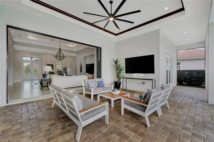 Tiled living room featuring a tray ceiling and ceiling fan with notable chandelier