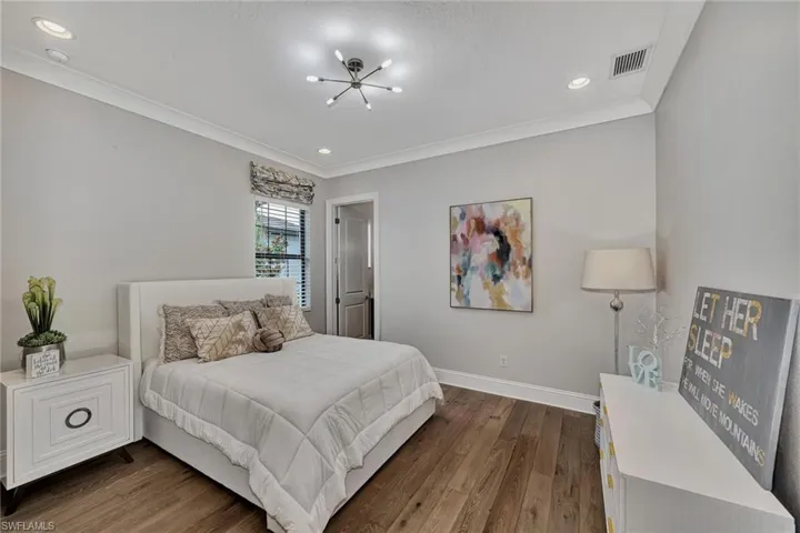 Bedroom with dark hardwood / wood-style floors, ornamental molding, and a chandelier