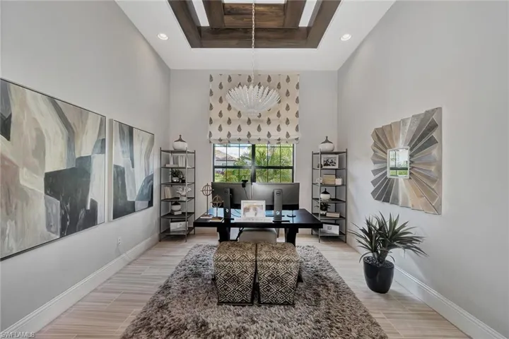 Home office featuring a high ceiling, wood-type flooring, and a raised ceiling