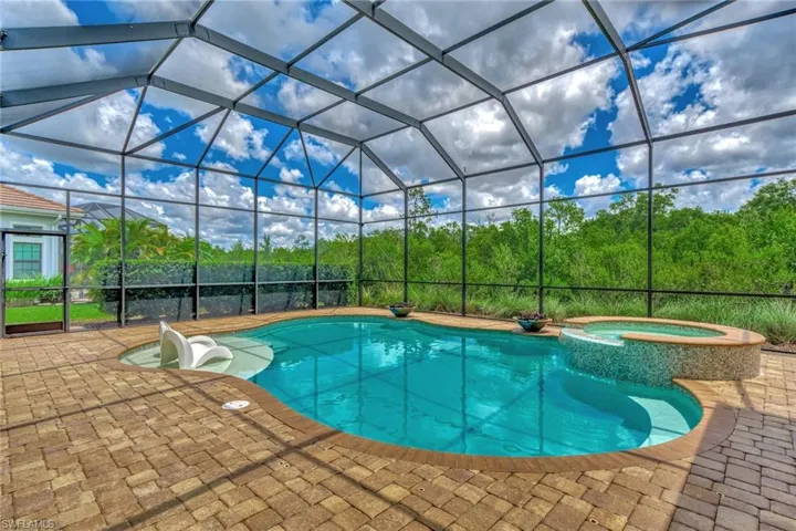 View of swimming pool featuring glass enclosure, an in ground hot tub, and a patio