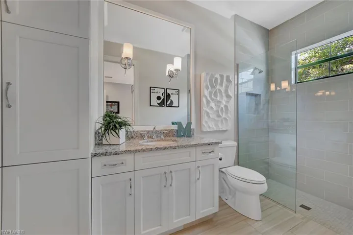 Bathroom with a shower with door, vanity, and toilet