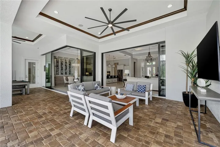 lanai featuring a raised ceiling, ceiling fan with notable chandelier, and dark tile floors