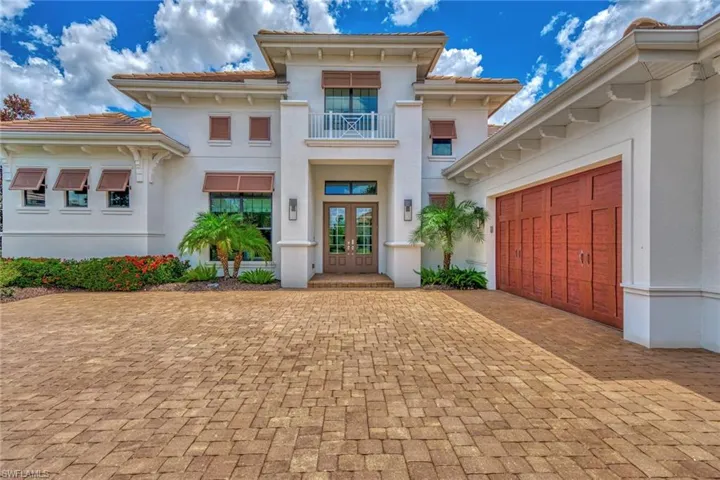 View of front of property featuring a garage, french doors, and a balcony