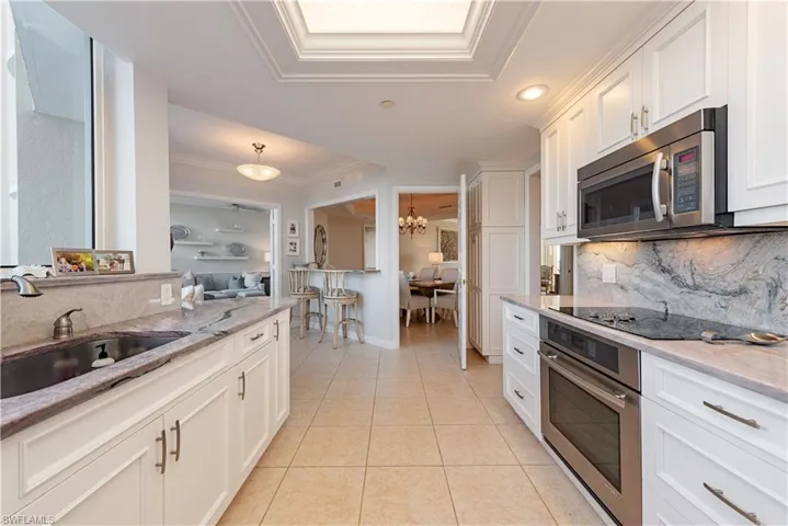 Kitchen with stainless steel appliances, sink, an inviting chandelier, backsplash, and white cabinets
