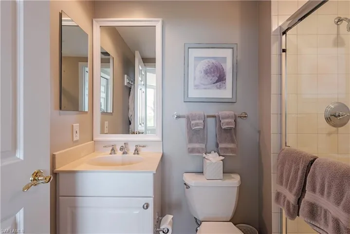 Bathroom with toilet, vanity, and a shower with door