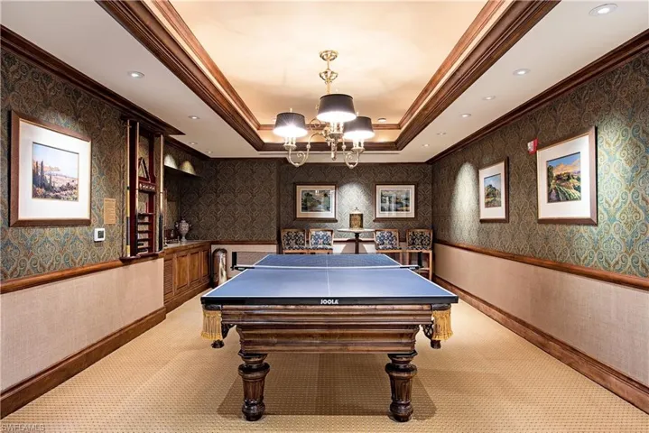 Game room with ornamental molding, light carpet, a raised ceiling, and an inviting chandelier