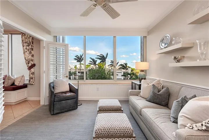 Tiled living room with ceiling fan and ornamental molding