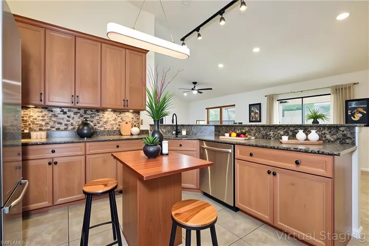 Kitchen featuring a breakfast bar, vaulted ceiling, appliances with stainless steel finishes, track lighting, and backsplash