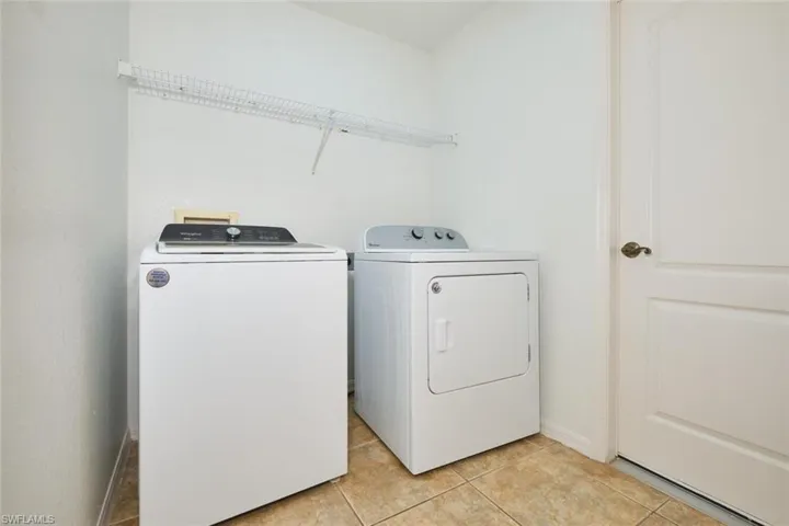Laundry area with light tile patterned floors and washing machine and clothes dryer