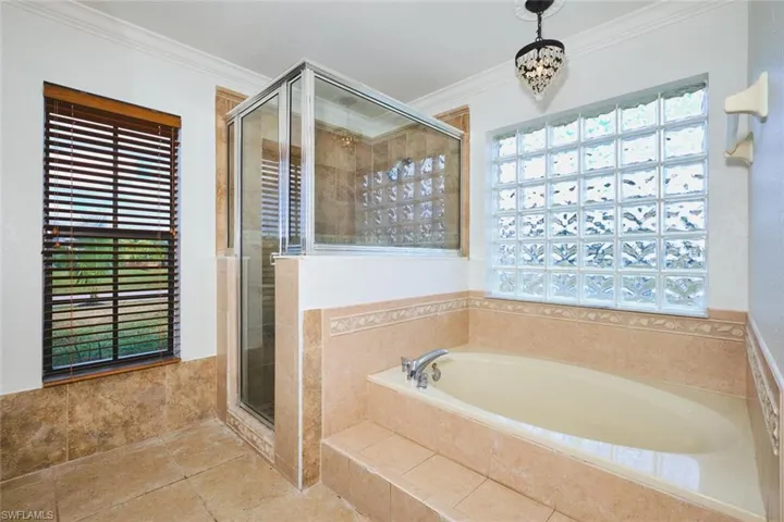 Bathroom with ornamental molding, a garden tub, a stall shower, and tile patterned flooring