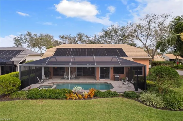 Rear view of house with roof mounted solar panels, screened pool/lanai