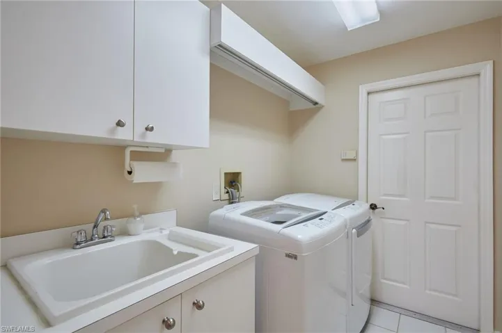 Laundry area with a sink, cabinet space, light tile floors, and washer and dryer