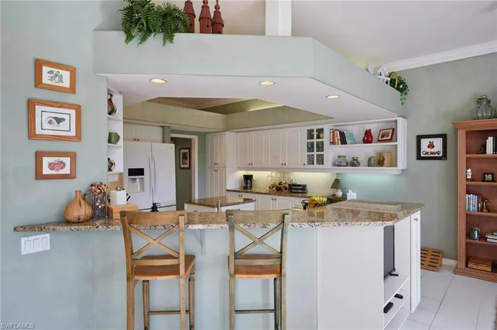 Kitchen bar view showing open shelves, glass insert cabinets, white cabinetry,