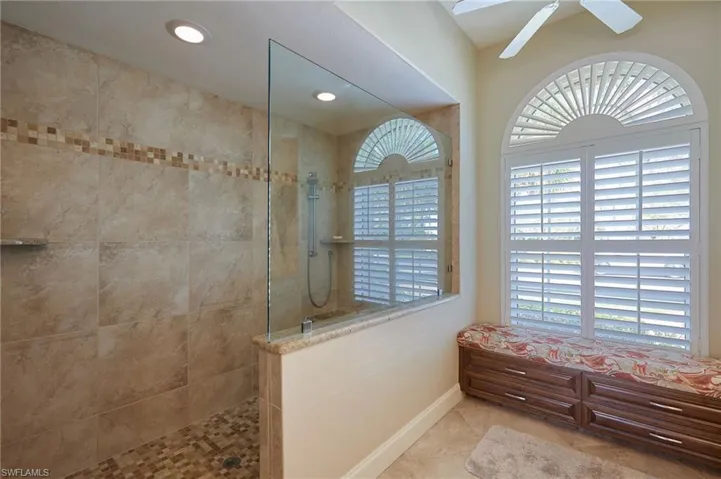 Custom walk-in shower, recessed lighting, a ceiling fan, & plantation shutters