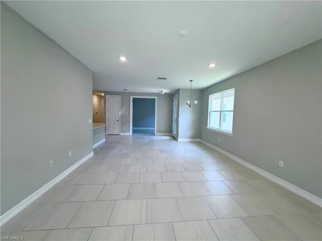 Unfurnished living room featuring a chandelier, recessed lighting, and light tile patterned floors
