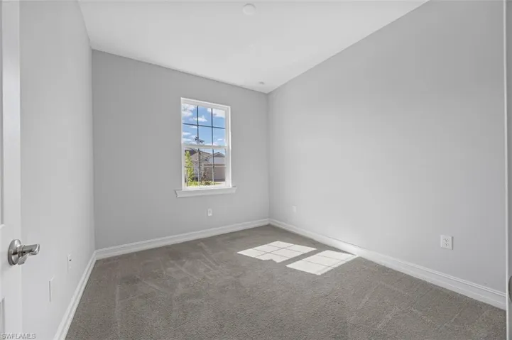 Carpeted spare room featuring baseboards