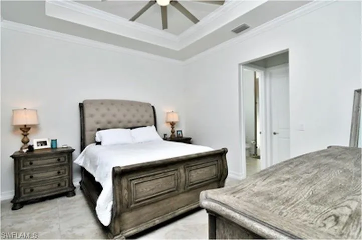 Bedroom featuring a tray ceiling, crown molding, and ceiling fan