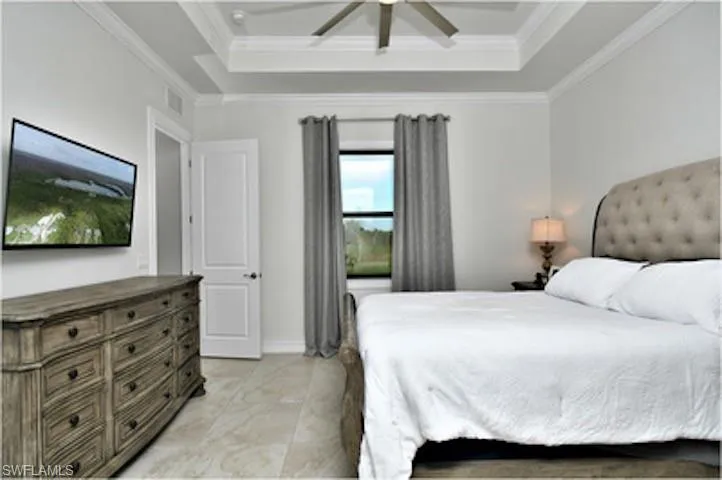 Bedroom featuring a raised ceiling, a ceiling fan, and crown molding