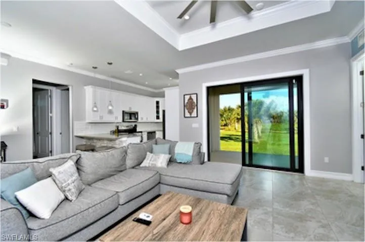 Living room featuring ornamental molding, a tray ceiling, recessed lighting, and a ceiling fan