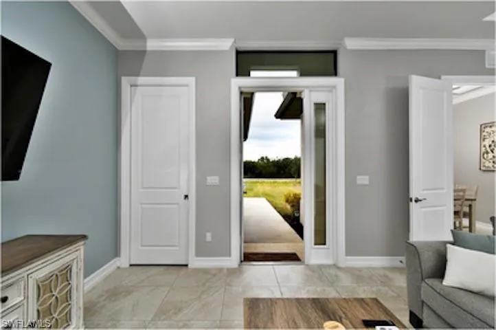 Entrance foyer with crown molding and light tile patterned flooring