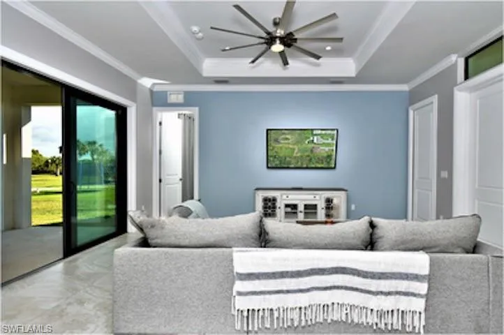 Living area with ornamental molding, a raised ceiling, and ceiling fan