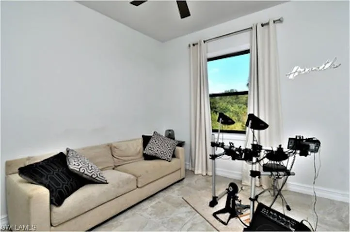 Living area featuring baseboards and ceiling fan