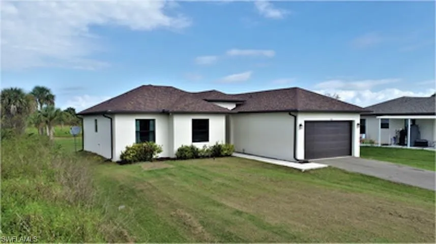 View of front of property with a garage, stucco siding, concrete driveway, and a front lawn
