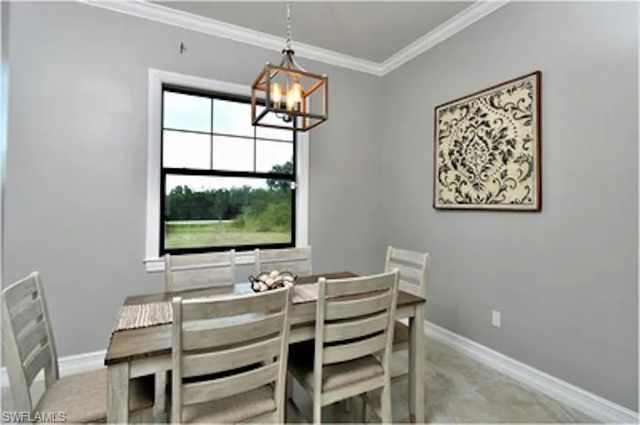 Dining area with ornamental molding, light colored carpet, and a chandelier