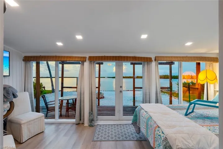 Bedroom with a water view, access to outside, french doors, wood finished floors, and recessed lighting