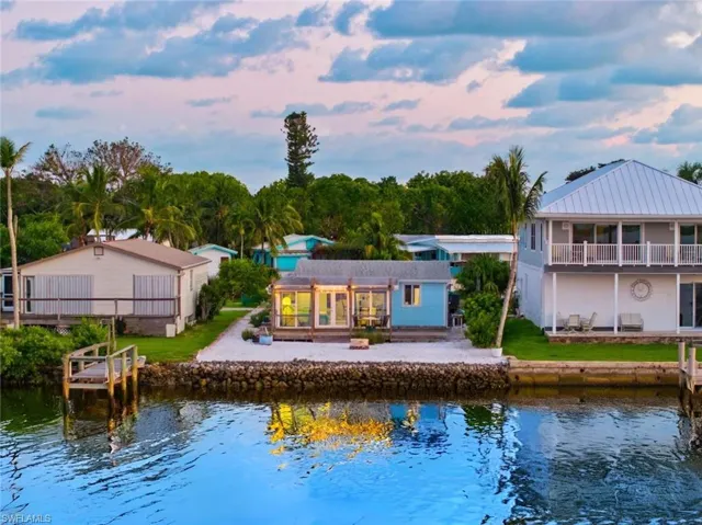 Back of house at dusk with a water view and a patio