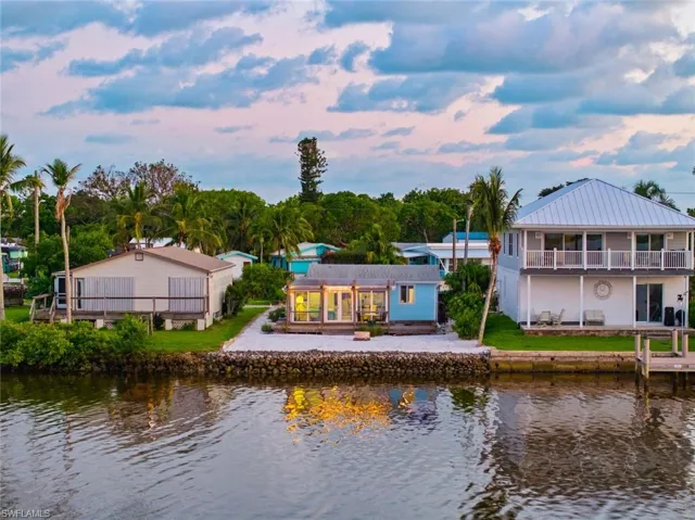 Back of house at dusk with a water view and a patio