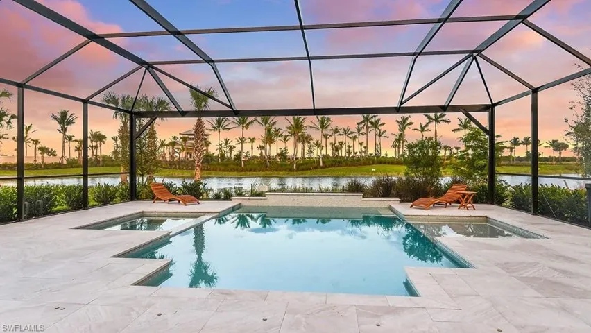 Outdoor pool featuring a patio area, a water view, and glass enclosure