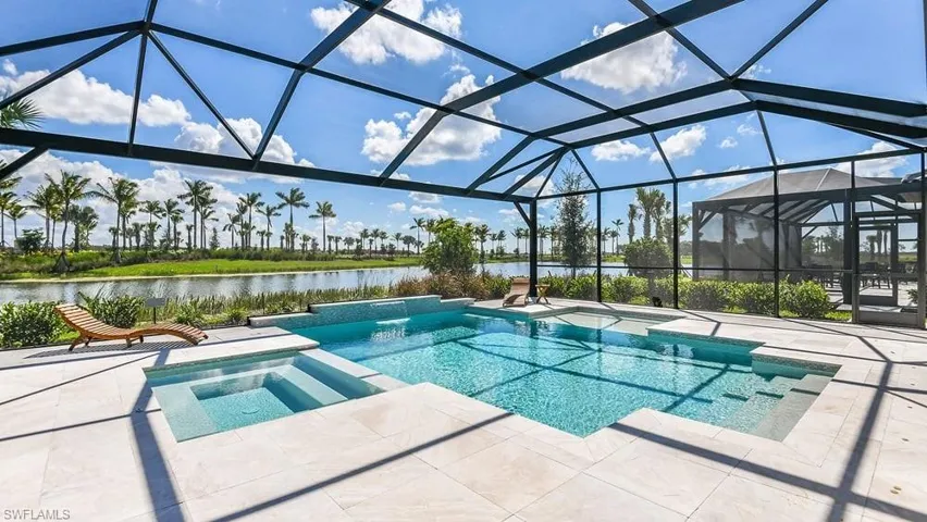View of swimming pool with a pool with connected hot tub, a patio, a water view, and a lanai