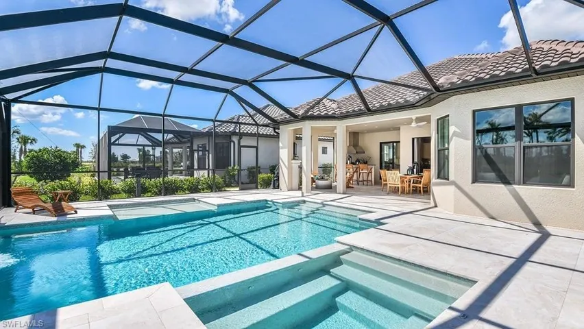 View of swimming pool with a pool with connected hot tub, a lanai, a patio, outdoor dining space, and ceiling fan