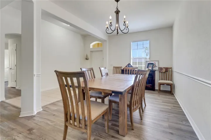 Dining space featuring arched walkways, a chandelier, and light wood-type flooring