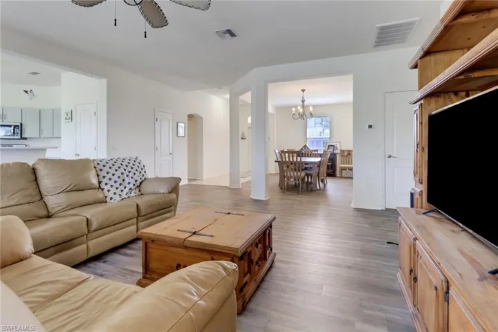 Living area with wood finished floors, ceiling fan, a chandelier, and arched walkways