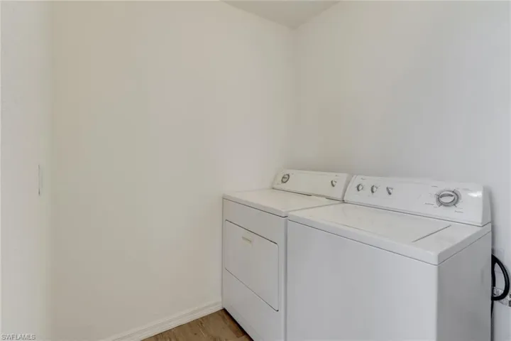 Laundry room with washing machine and dryer and light wood-style flooring