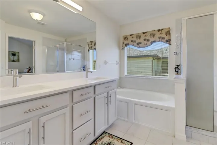 Full bathroom featuring a stall shower, double vanity, a bath, and tile patterned floors