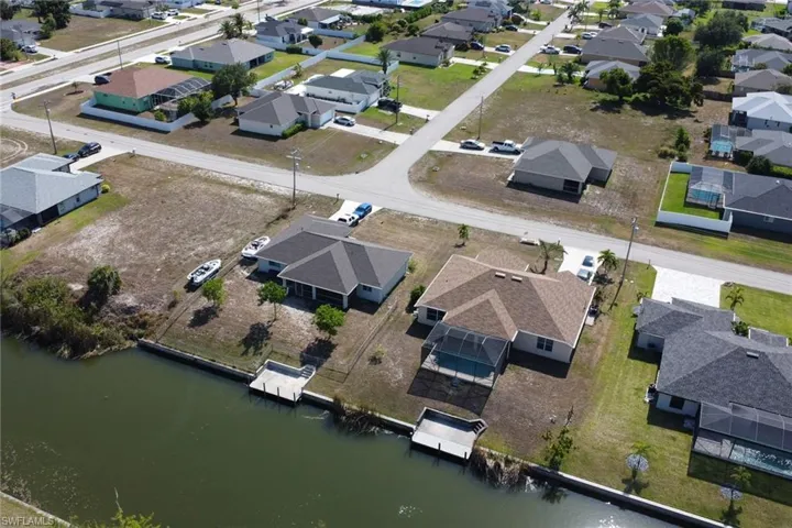 Aerial view of property and surrounding area featuring nearby suburban area and a nearby body of water