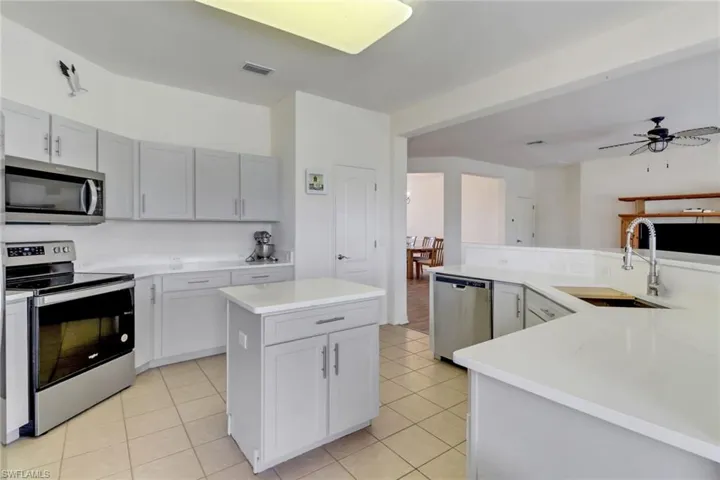 Kitchen featuring appliances with stainless steel finishes, a center island, light countertops, and light tile patterned flooring
