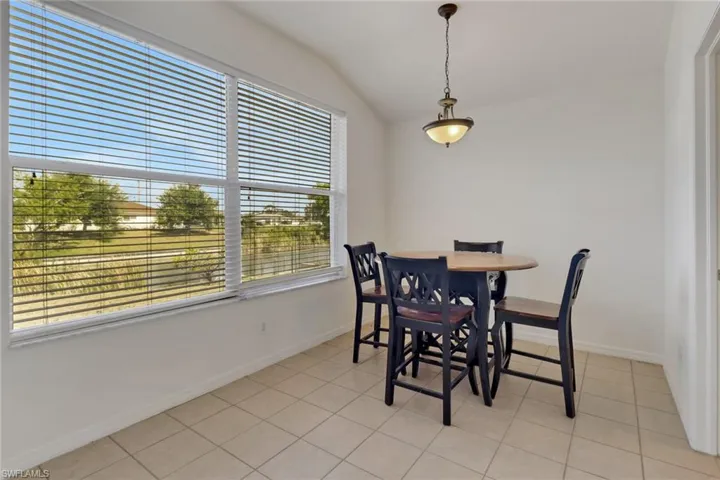 Dining space featuring healthy amount of natural light, vaulted ceiling, and light tile patterned flooring