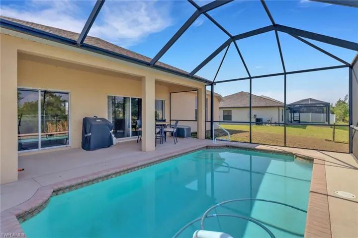 Swimming pool with a patio area, a yard, and glass enclosure