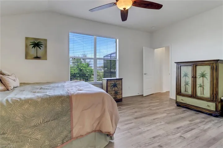 Bedroom with light wood-style flooring, vaulted ceiling, and a ceiling fan