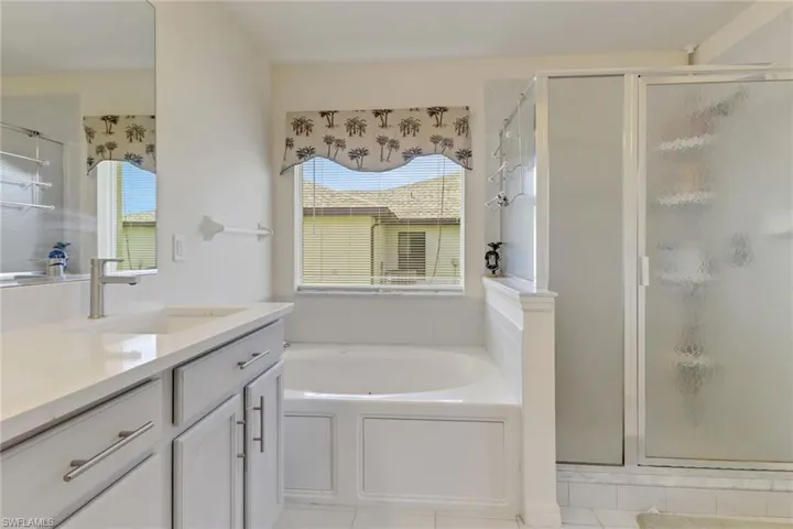 Full bath featuring vanity, a shower stall, and a garden tub