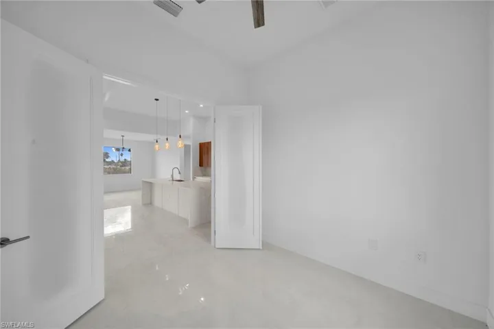 Unfurnished bedroom featuring light marble finish flooring, a ceiling fan, and suspended lighting