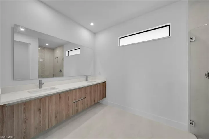 Bathroom with double vanity, a stall shower, and recessed lighting