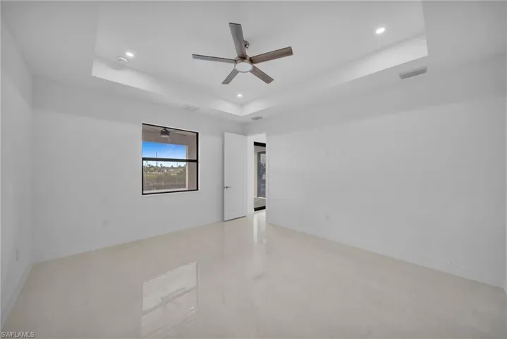 Unfurnished room with a raised ceiling, recessed lighting, and a ceiling fan
