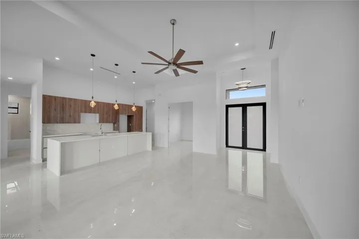 Kitchen with modern cabinets, a large island, open floor plan, hanging light fixtures, and a high ceiling